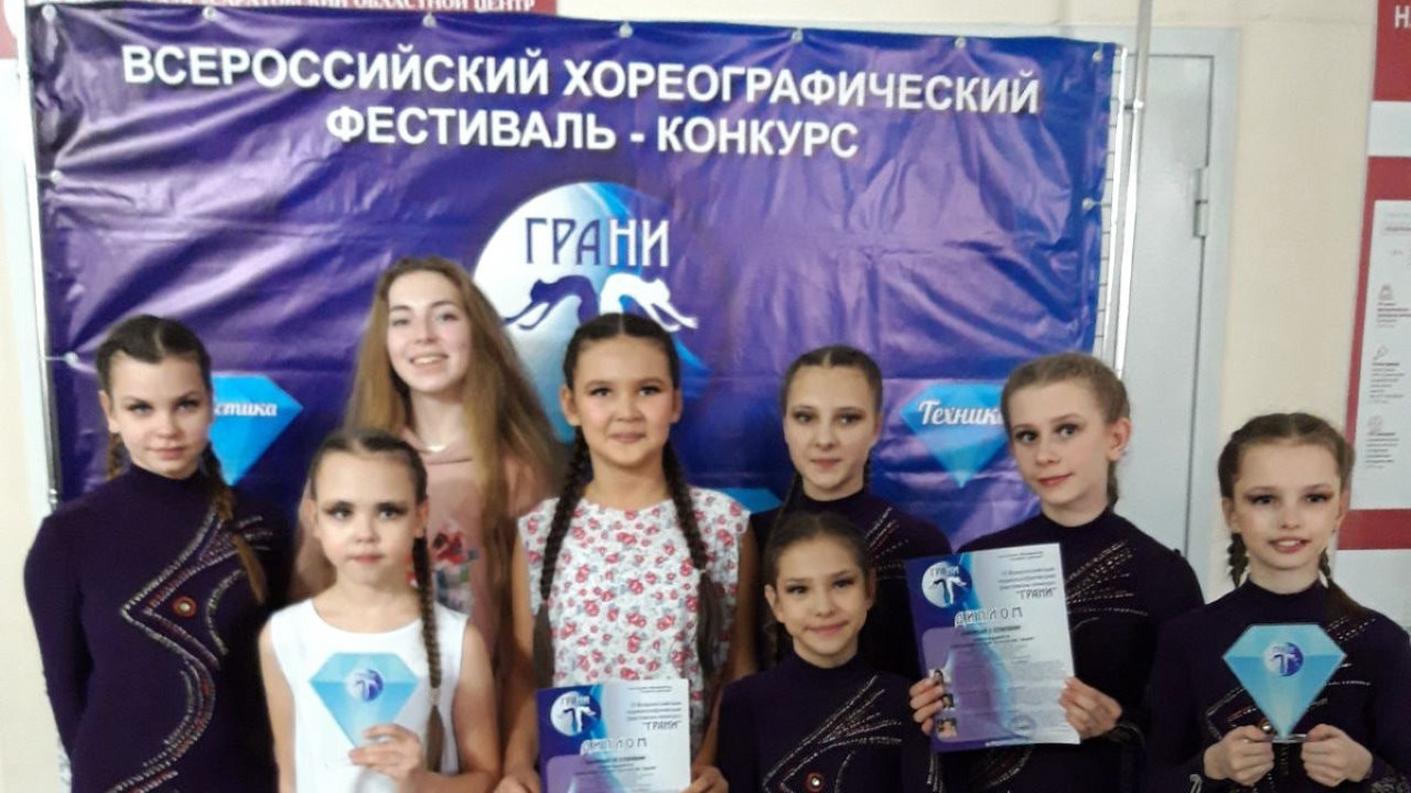 Девочки на фоне баннера конкурса Грани в 2022 году